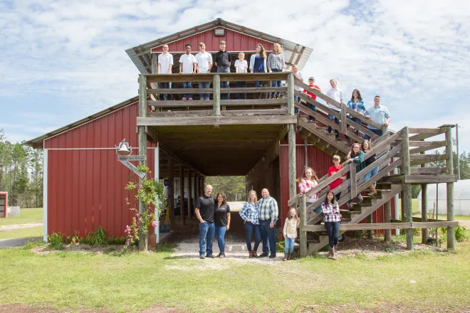 Several families posing for a photo at a barn