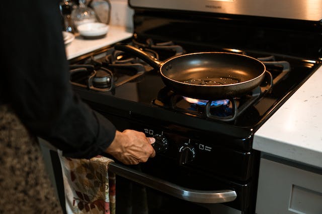 A man heating up a stove top so he can start cooking